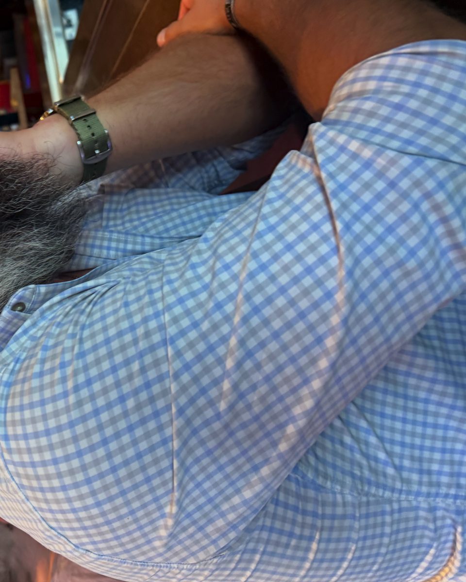 Adam Olson wearing glasses and a blue checkered shirt inside a warmly lit restaurant