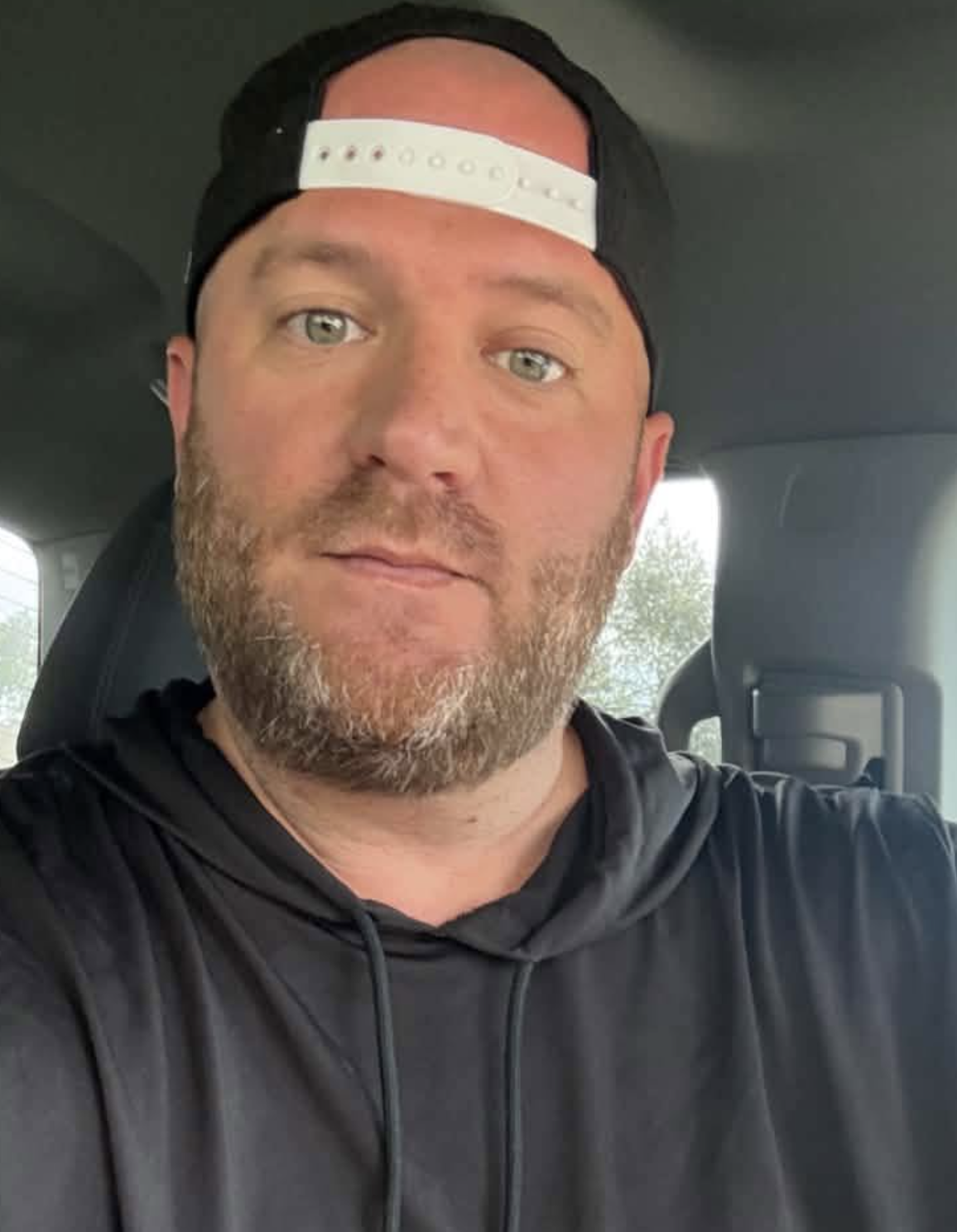 Will H taking a portrait selfie while wearing a backwards cap and black hoodie